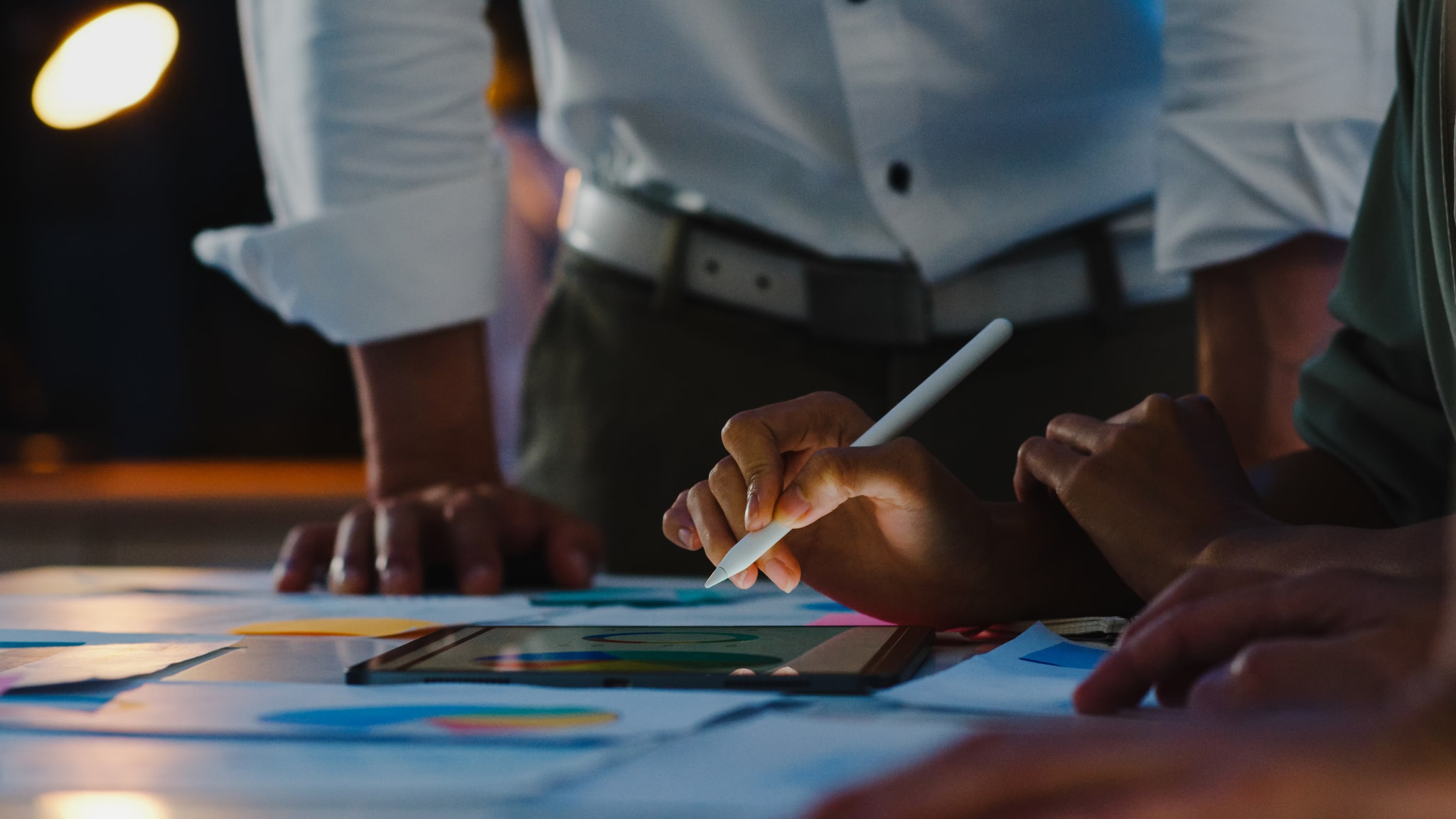 Team collaborating over analytics charts and a tablet during a strategy session